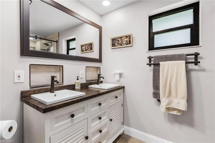 Bathroom featuring double vanity, wood finished floors, and a shower