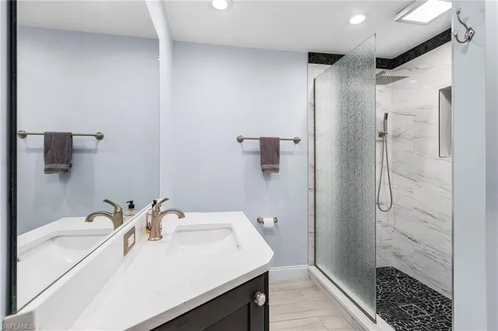 Full bath with vanity, a marble finish shower, and recessed lighting
