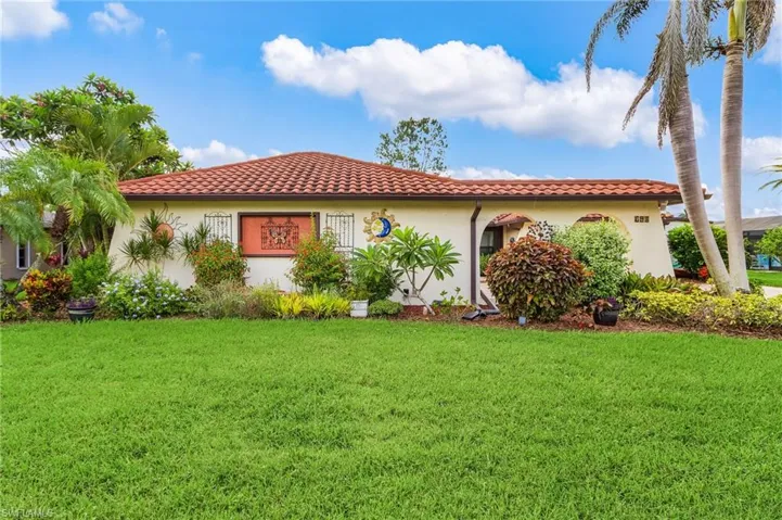 Mediterranean / spanish home with a well maintained front yard, stucco siding, and a tiled roof