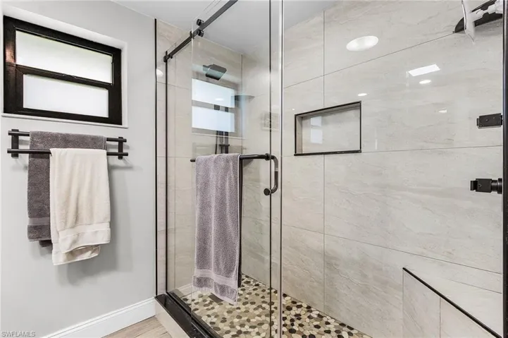 Bathroom with a shower stall and baseboards