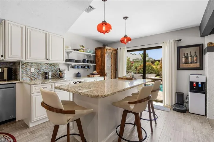 Kitchen with dishwasher, a breakfast bar, light wood finished floors, and backsplash