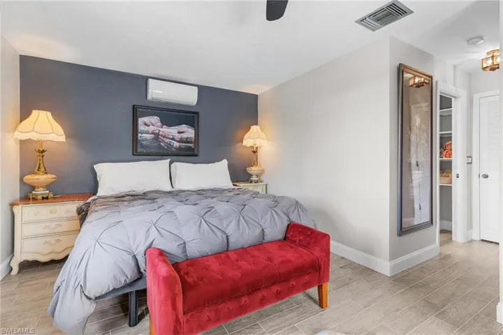 Bedroom featuring wood finish floors, a wall mounted air conditioner, and ceiling fan