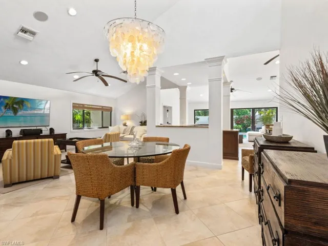 Dining space featuring decorative columns, a wealth of natural light, visible vents, and ceiling fan with notable chandelier
