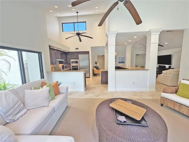 Living room with recessed lighting, ceiling fan, ornate columns, and a high ceiling