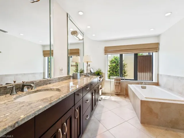 Bathroom featuring a sink, tile patterned flooring, double vanity, recessed lighting, and a relaxing tiled tub
