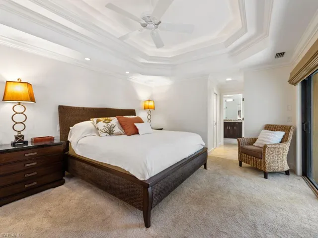 Bedroom with visible vents, ensuite bathroom, a raised ceiling, ornamental molding, and light carpet