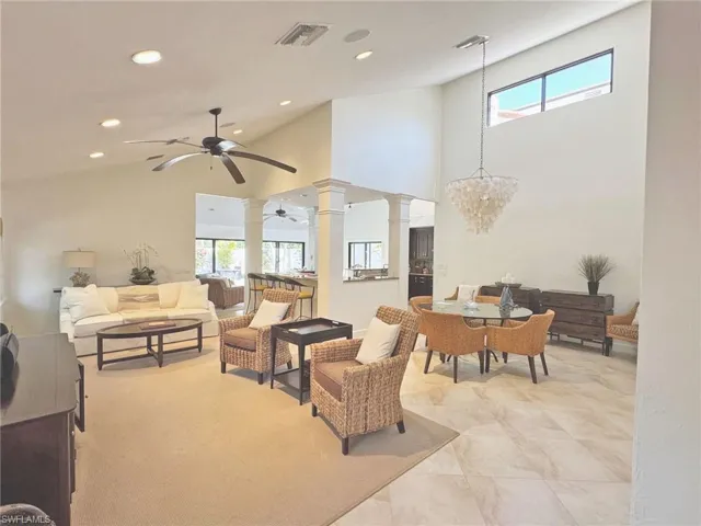 Living area with a healthy amount of sunlight, decorative columns, ceiling fan with notable chandelier, and visible vents