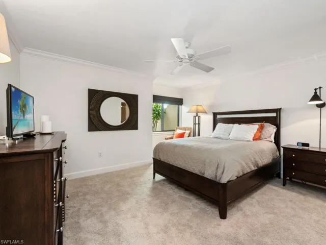 Bedroom featuring a ceiling fan, light colored carpet, baseboards, and ornamental molding