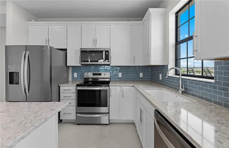 Island feat quartz countertops, stylish backsplash, and stainless steel appliances!