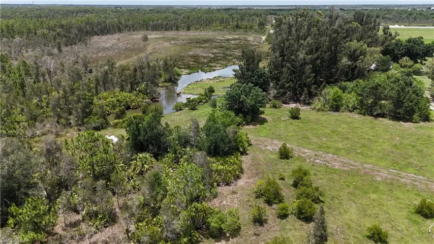 Aerial overview of property's location with a nearby body of water and a forest