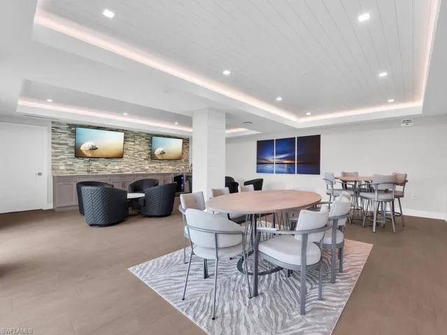Dining area with a raised ceiling, light wood-style floors, and recessed lighting