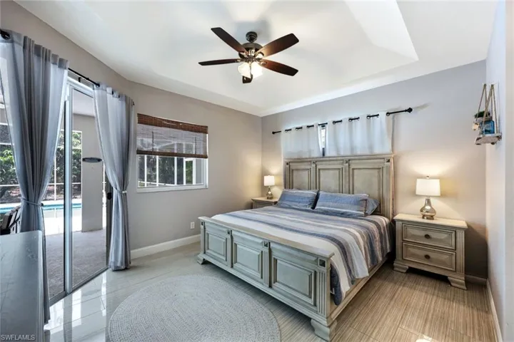 Bedroom with access to exterior, a tray ceiling, and a ceiling fan