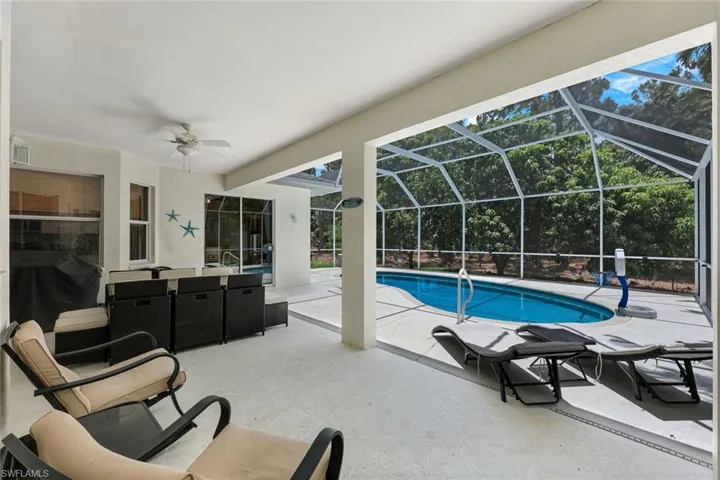 Outdoor pool with a patio area, ceiling fan, grilling area, and a lanai