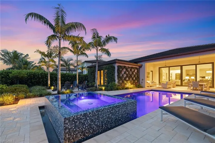 Pool at dusk with an in ground hot tub and a patio