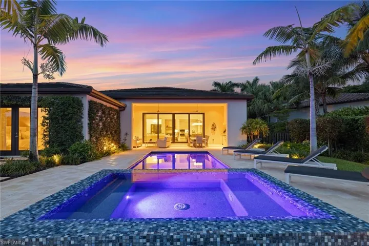 Pool at dusk featuring a patio and an in ground hot tub
