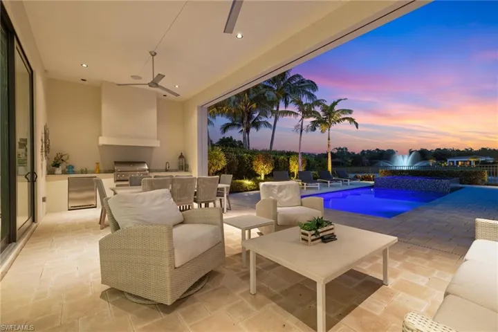 Patio terrace at dusk featuring exterior kitchen, ceiling fan, and grilling area