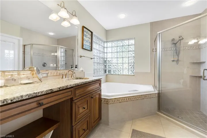 Master Bathroom with vanity, a shower stall, a bath, and light tile patterned floors