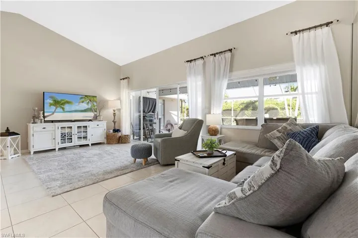 Living area with light tile patterned floors and high vaulted ceiling