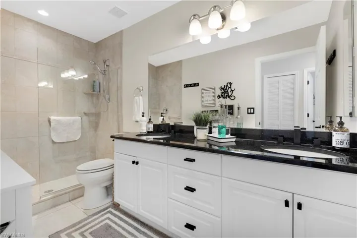 Full bath #2 featuring double vanity, a tile shower, and light tile patterned floors