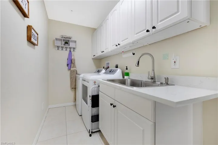 Laundry area featuring cabinet space, light tile patterned floors, and independent washer and dryer