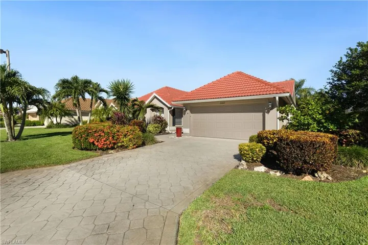 View of front of home with a front yard, a tile roof, decorative driveway, an attached 2 car garage, and stucco siding