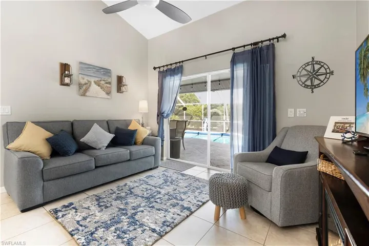 Living room featuring light tile patterned floors, high vaulted ceiling, and ceiling fan