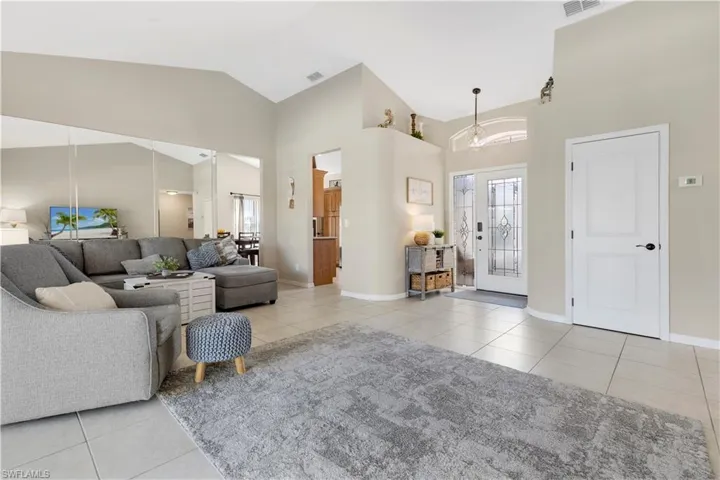 Living room featuring light tile patterned flooring, high vaulted ceiling, and french doors
