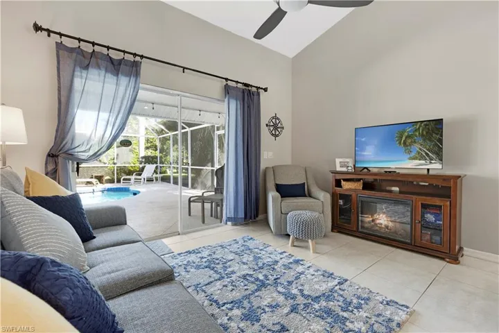 Living area with light tile patterned floors, a ceiling fan, and a high vaulted ceiling