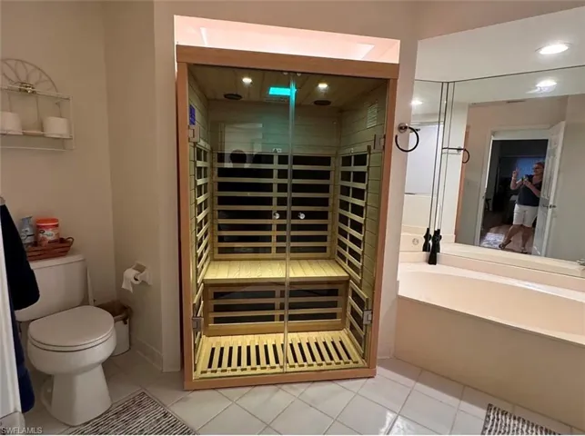 Bathroom featuring a built-in sauna with a glass door, a bathtub, and a toilet