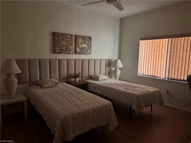 This room features hardwood flooring, a ceiling fan, and window blinds