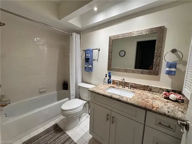 Bathroom featuring a white vanity with a rectangular undermount sink, a polished chrome faucet, and a stone-finish countertop