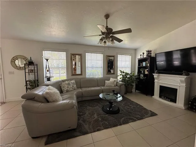 Tiled living room featuring ceiling fan and a textured ceiling