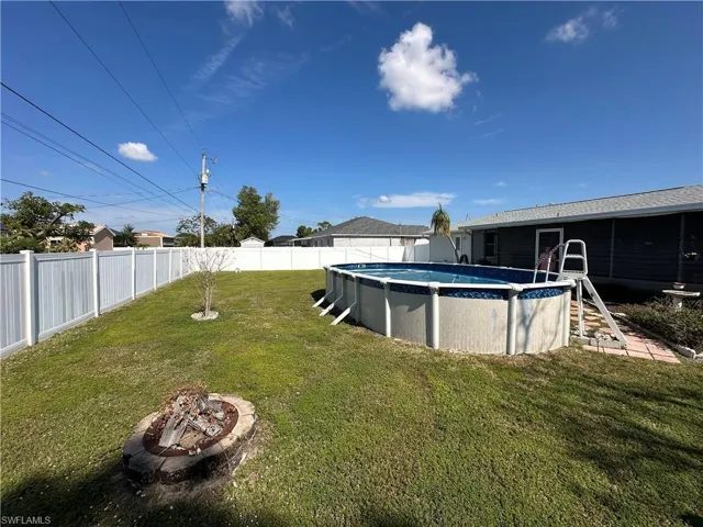 View of yard with Vinyl fencing, pool and a fire pit
