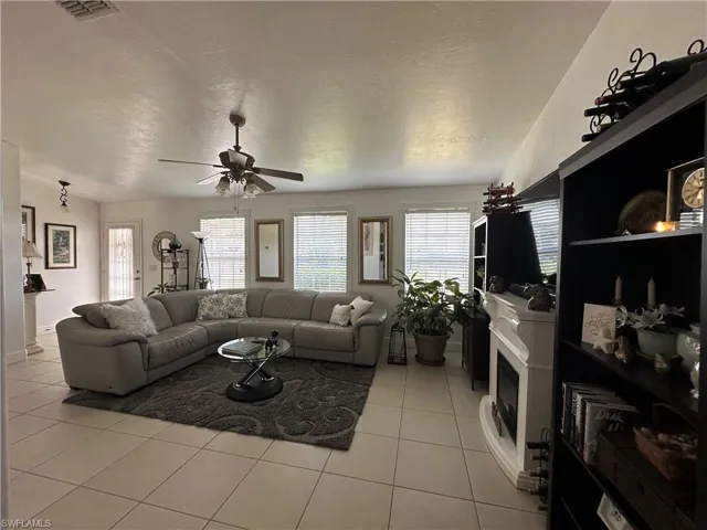 Living room with light tile patterned floors, a textured ceiling, and ceiling fan