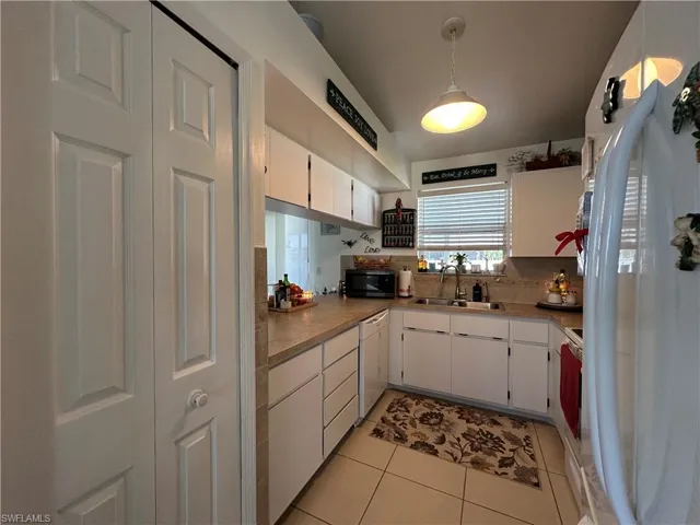 Kitchen featuring Pantry, white appliances, light tile patterned floors, white cabinetry, and decorative backsplash