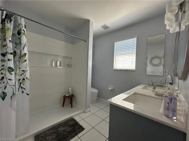 Bathroom featuring vanity, tile patterned flooring, a shower with curtain, and toilet