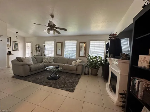Living room with light tile patterned flooring, ceiling fan, and a textured ceiling