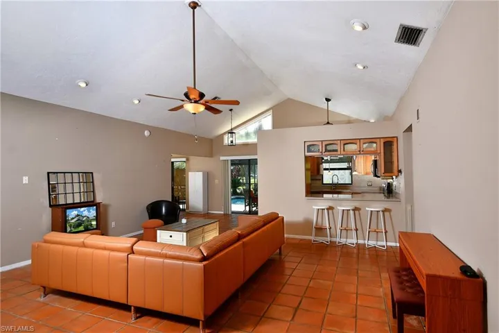 Tiled living area with ceiling fan, high vaulted ceiling, and recessed lighting