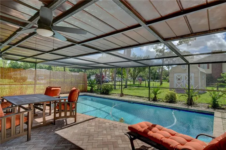 View of swimming pool featuring a storage shed, ceiling fan, a patio, and a lanai