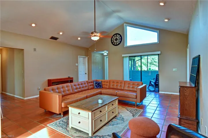 Tiled living room with a ceiling fan, recessed lighting, and high vaulted ceiling
