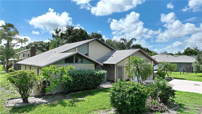 Mid-century modern home with driveway, a front yard, stucco siding, and roof with shingles