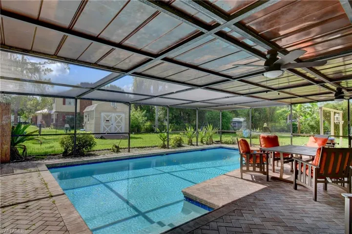 Swimming pool featuring a storage shed, a yard, a ceiling fan, and a patio