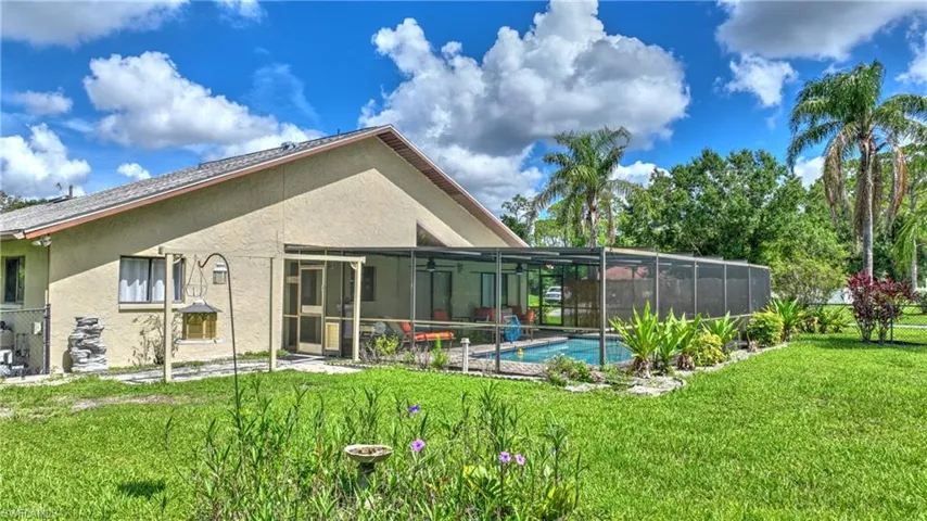 Rear view of house featuring stucco siding, an outdoor pool, and a lanai