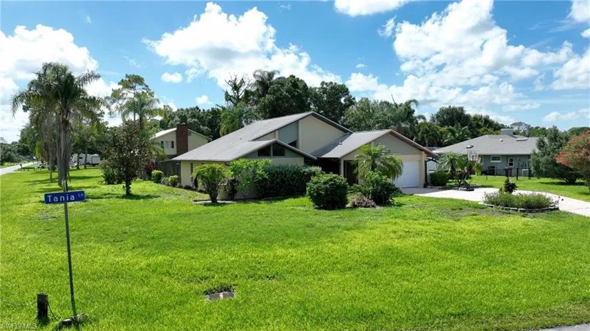 View of front facade with driveway, an attached garage, a front yard, and a residential view