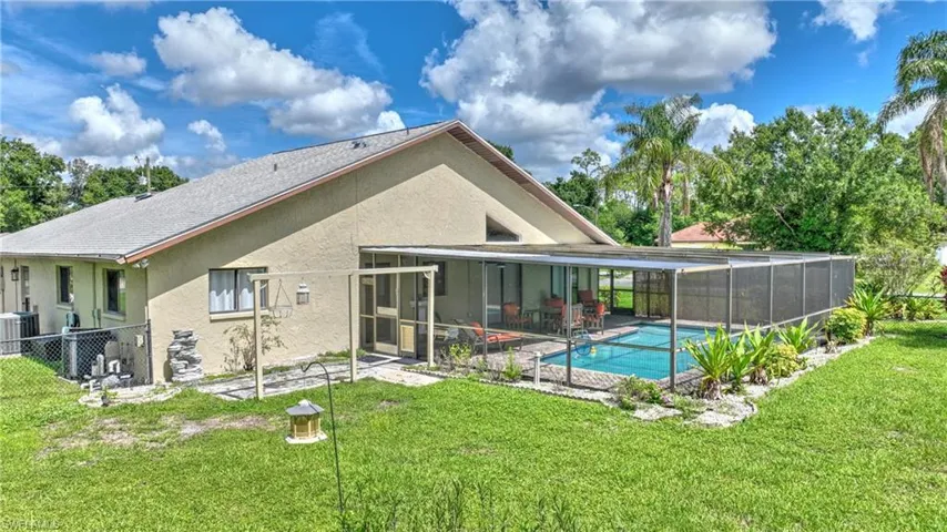 Rear view of property featuring stucco siding, a patio area, and glass enclosure