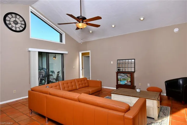 Living area with tile patterned flooring, ceiling fan, and high vaulted ceiling