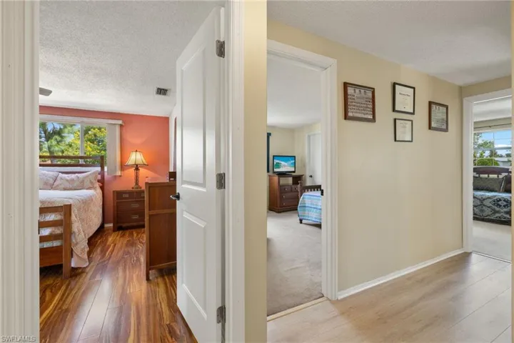 Hall featuring a healthy amount of sunlight, light colored carpet, and a textured ceiling