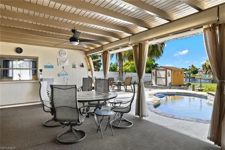 View of patio / terrace with ceiling fan, a fenced in pool, and a shed