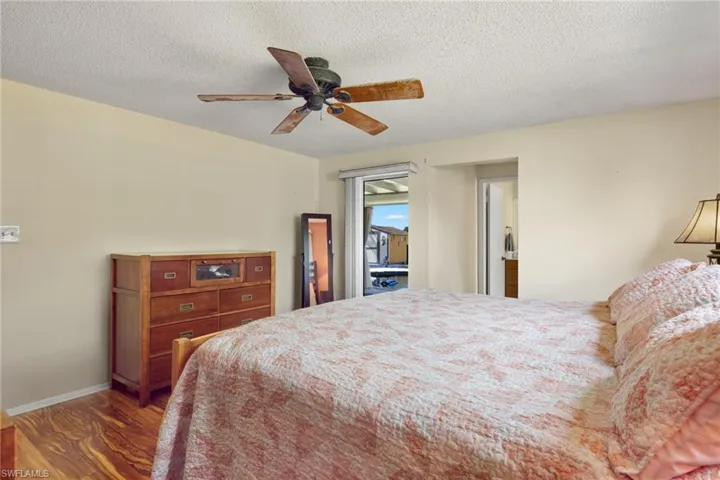 Primary Bedroom with ceiling fan, dark hardwood / wood-style floors, and a textured ceiling