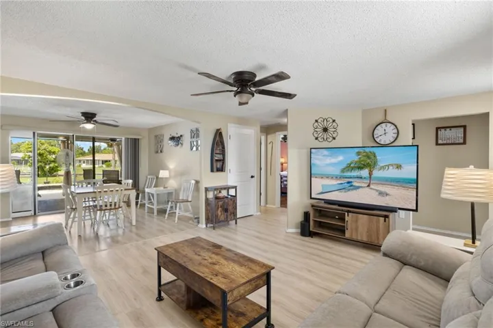 Living room featuring a textured ceiling, ceiling fan, and light hardwood / wood-style floors